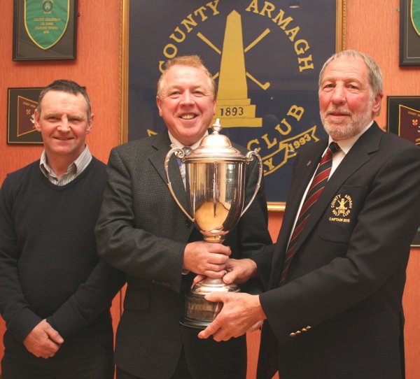 Gerry Doyle is presented with the magnificent CP McNabb Trophy by County Armagh Golf Club Captain John Flack. Looking on is competition runner-up Anthony Fegan